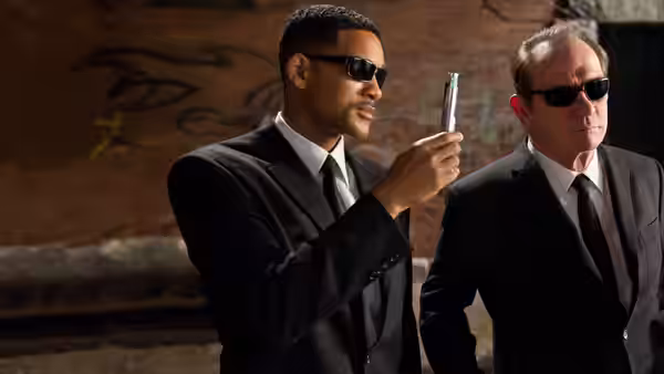 Agent J (Will Smith) examines a device beside Agent K (Tommy Lee Jones) in a tunnel
