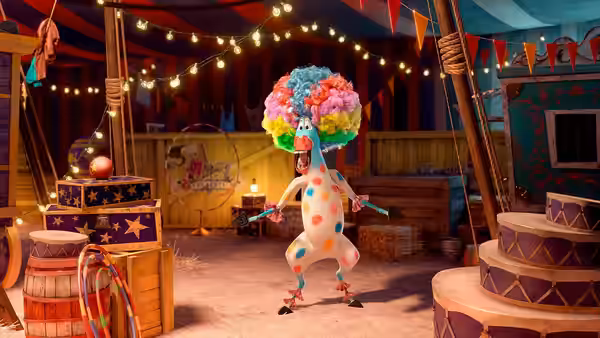A clown-costumed animal performs in a circus tent among barrels and props