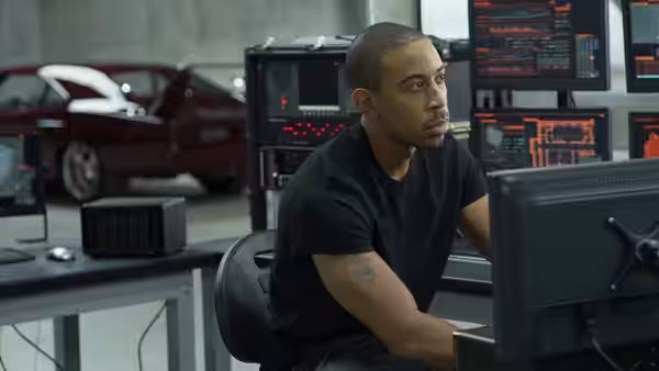 Tej Parker (Ludacris) works at a computer in a room filled with equipment and cars