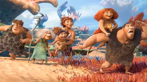 The Croods flee across colorful terrain as Grug carries Eep on his shoulders
