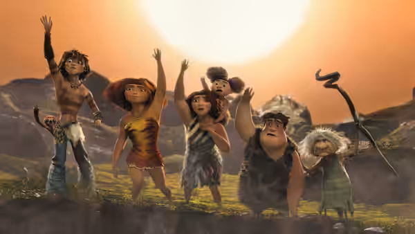 Guy and the Crood family raise their arms beneath a blazing sunset