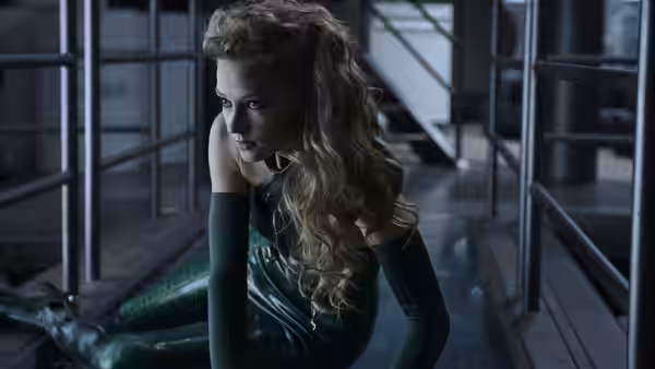 Viper (Svetlana Khodchenkova) crouches in a green suit inside a metal corridor