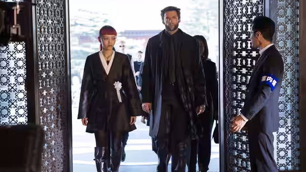 Logan (Hugh Jackman) and Yukio (Rila Fukushima) enter a building as a uniformed guard waits