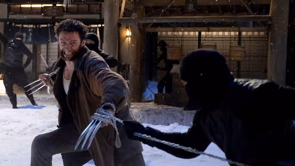 Logan (Hugh Jackman) extends his claws against a masked attacker in a snow-covered courtyard