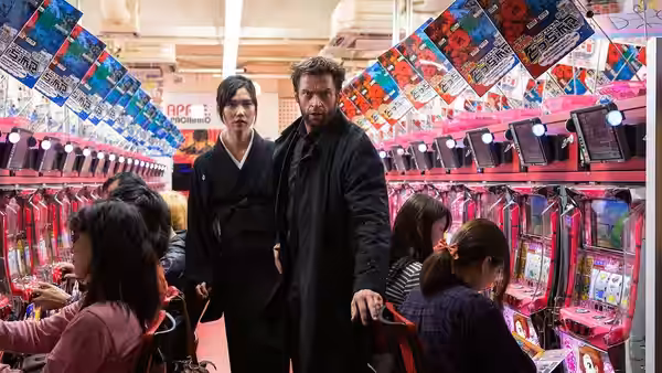 Logan (Hugh Jackman) and Mariko (Tao Okamoto) walk through a crowded Japanese pachinko arcade