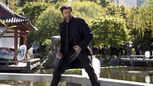 Logan (Hugh Jackman) stands ready with claws extended beside a garden pond