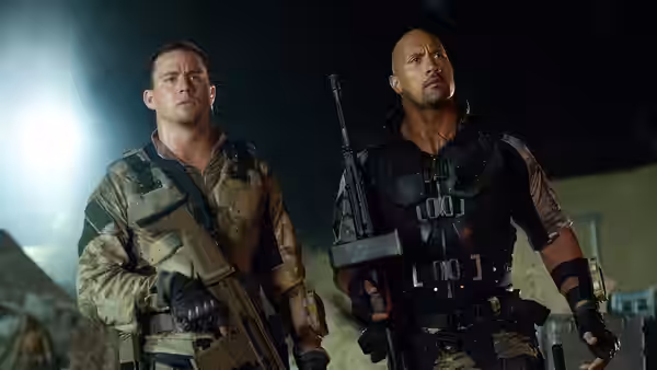 Flint (D.J. Cotrona) and Roadblock (Dwayne Johnson) walk forward carrying rifles