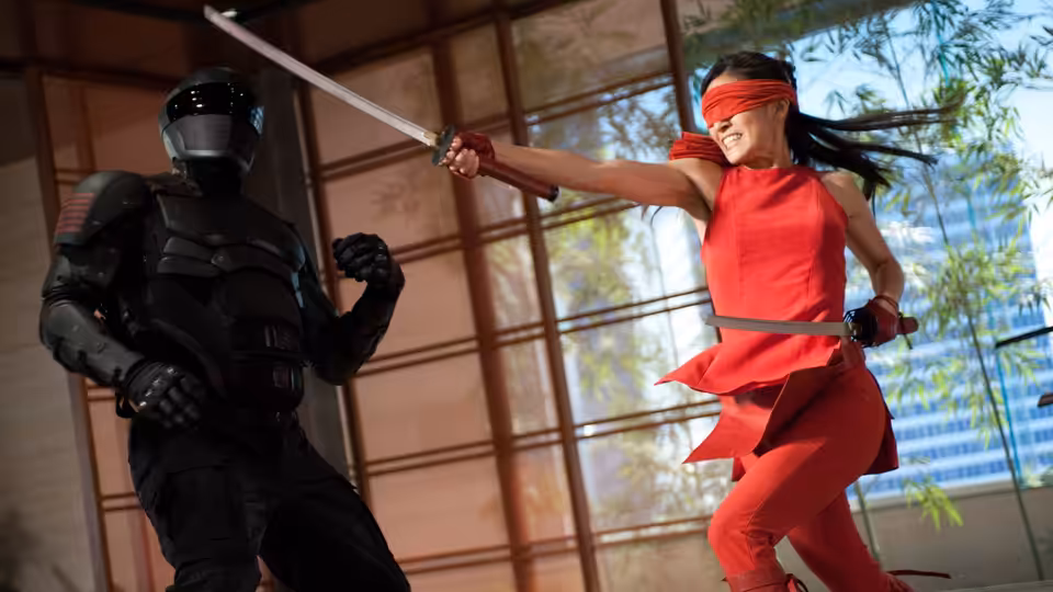 Jinx (Élodie Yung) swings a sword at an armored opponent inside a glass-walled dojo
