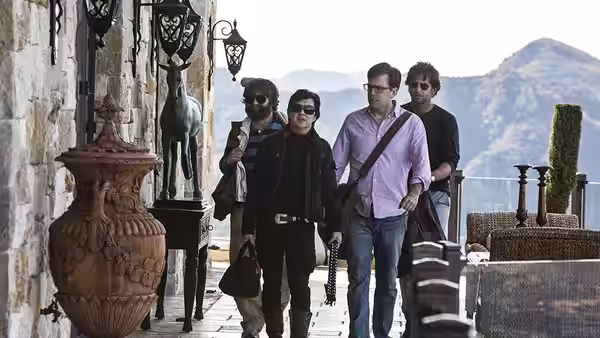 Mr. Chow leads Phil, Stu and Alan along a stone terrace