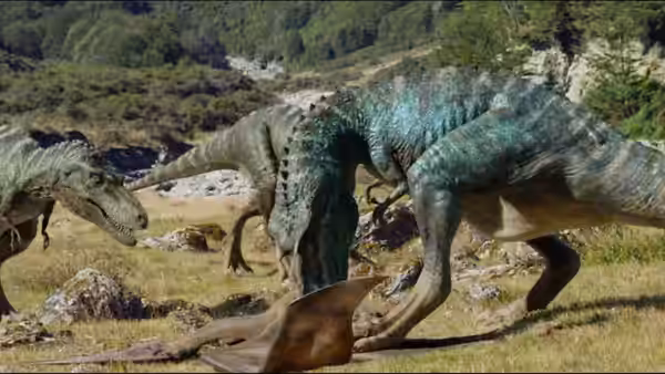 A blue theropod bends over a fallen dinosaur as another approaches