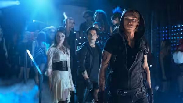 Jace Wayland (Jamie Campbell Bower) leads companions through a blue-lit nightclub