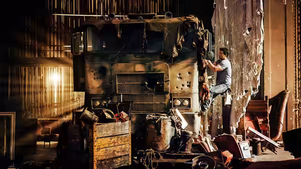 Cade Yeager (Mark Wahlberg) climbs the side of a battered truck in a workshop