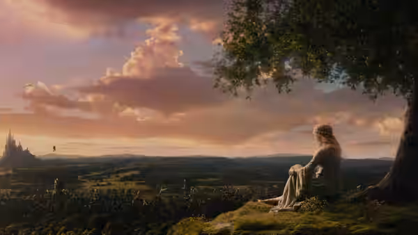 Aurora (Elle Fanning) sits beneath a tree overlooking a distant castle and countryside