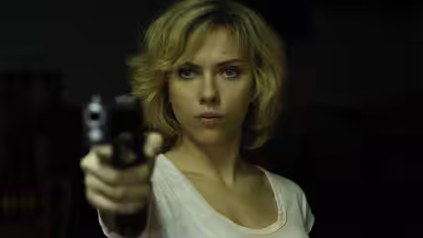 Lucy (Scarlett Johansson) points a handgun toward someone in a dark room