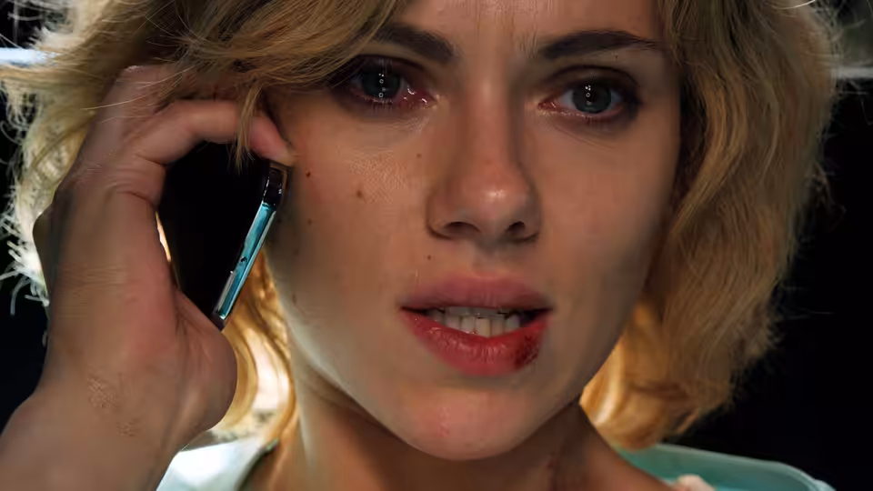 Lucy (Scarlett Johansson) holds a phone to her ear in close-up