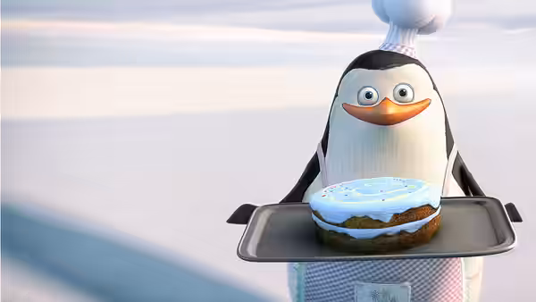 Private, dressed as a chef, carries a cake on a tray across the snow