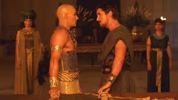 Moses (Christian Bale) and Ramses (Joel Edgerton) face each other across a table in the palace