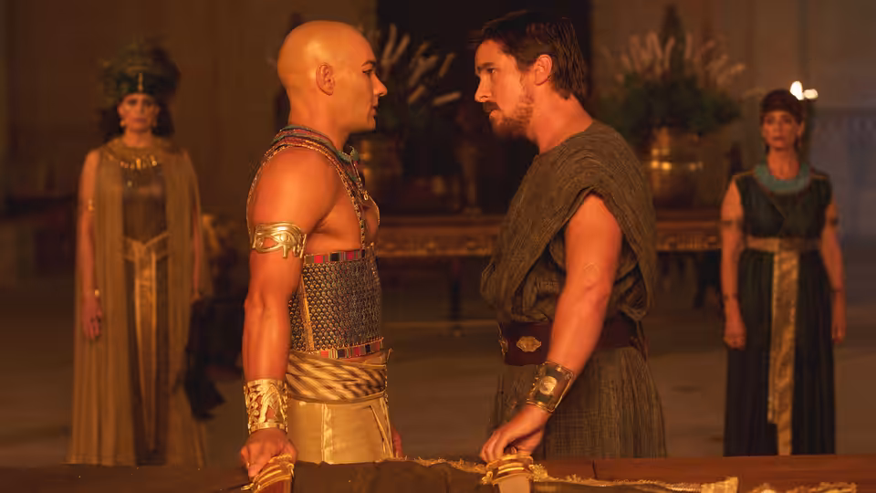 Moses (Christian Bale) and Ramses (Joel Edgerton) face each other across a table in the palace