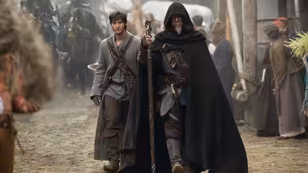 Tom Ward (Ben Barnes) walks through a crowded village beside Master John Gregory (Jeff Bridges)