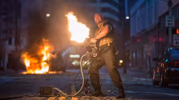 Luke Hobbs (Dwayne Johnson) fires a heavy machine gun on a city street