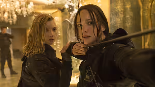 Katniss Everdeen (Jennifer Lawrence) and a blonde companion face danger in an ornate Capitol room