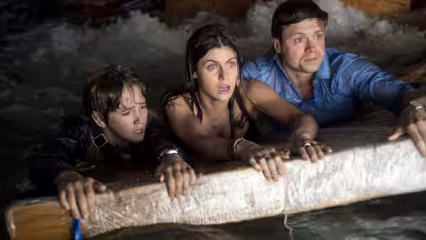 Blake Gaines (Alexandra Daddario), Ben Taylor (Hugo Johnstone-Burt), and Ollie Taylor (Art Parkinson) cling to a ledge above floodwater