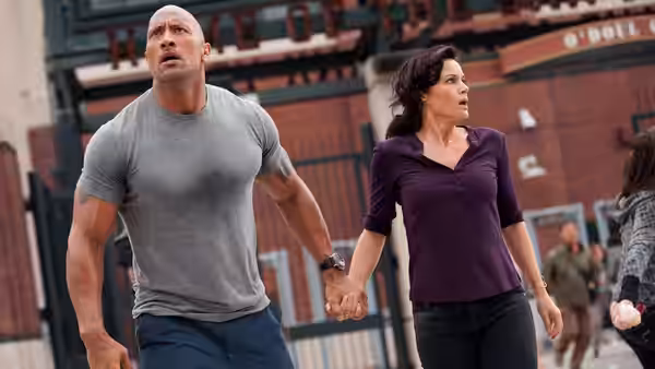 Ray Gaines (Dwayne Johnson) and Emma Gaines (Carla Gugino) hold hands in a crowded street