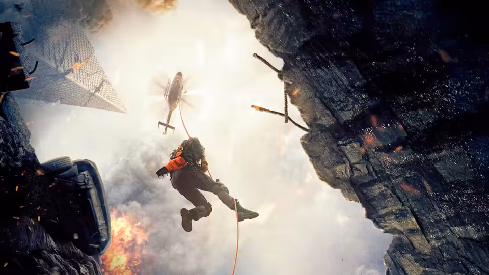A rescue worker descends on a cable through a collapsing building as a helicopter approaches