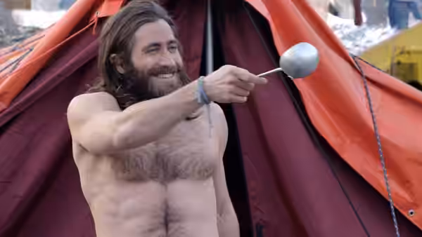 Scott Fischer (Jake Gyllenhaal) smiles and holds a spoon outside a tent