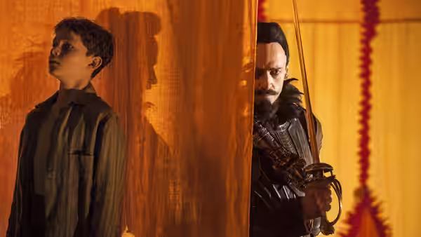 Peter Pan (Levi Miller) stands beside a curtain as Blackbeard (Hugh Jackman) watches from behind it