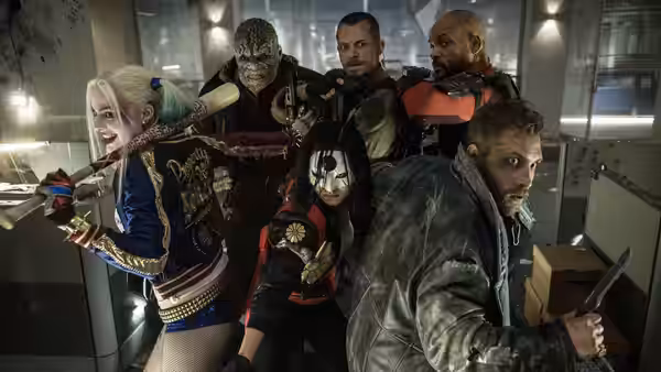 Harley Quinn and the squad crouch together inside a brightly lit industrial room
