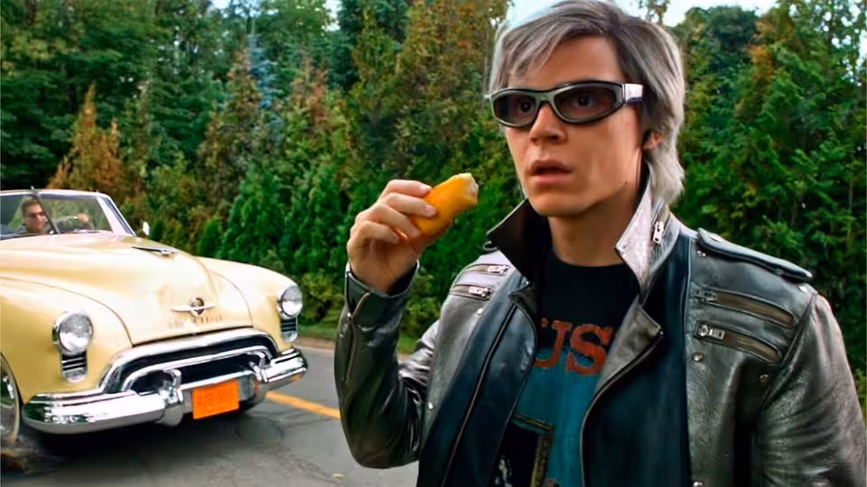 Peter Maximoff (Evan Peters) holds a snack beside a cream-colored car on a wooded road