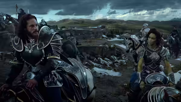 Anduin Lothar (Travis Fimmel) and Garona (Paula Patton) ride through a battlefield on horseback