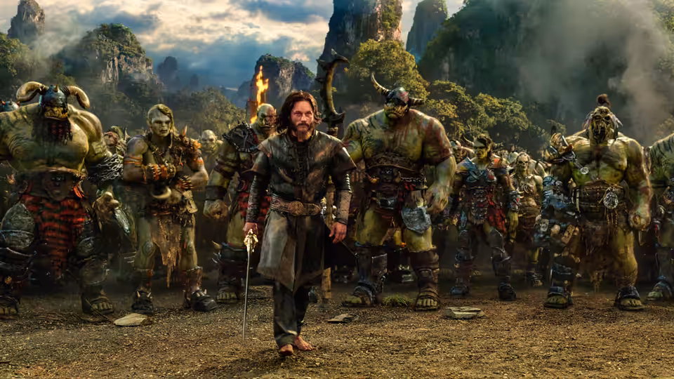 Anduin Lothar (Travis Fimmel) walks among a group of orc warriors in a mountain valley