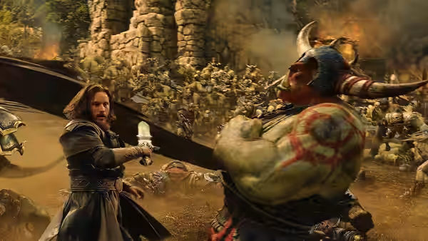 Anduin Lothar (Travis Fimmel) raises his sword against a horned orc amid a fortress battle