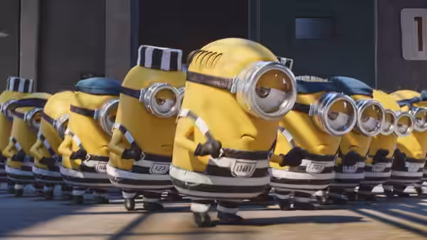 Minions in striped prison uniforms march together through a corridor