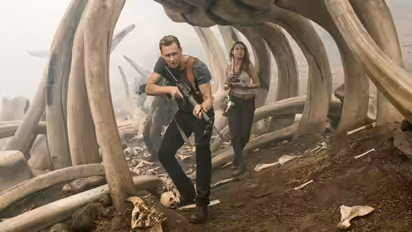 Captain James Conrad (Tom Hiddleston) and Mason Weaver move beneath enormous ribs, carrying rifles