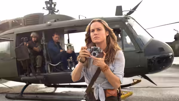 Mason Weaver (Brie Larson) holds a camera beside a military helicopter