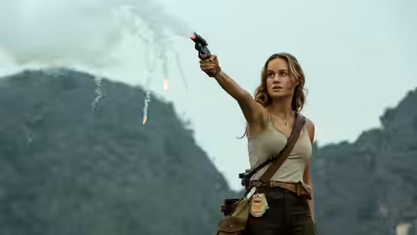 Mason Weaver (Brie Larson) raises a flare gun against a mountainous jungle backdrop