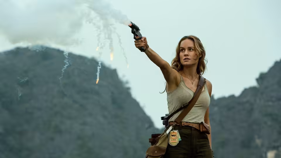 Mason Weaver (Brie Larson) raises a flare gun against a mountainous jungle backdrop