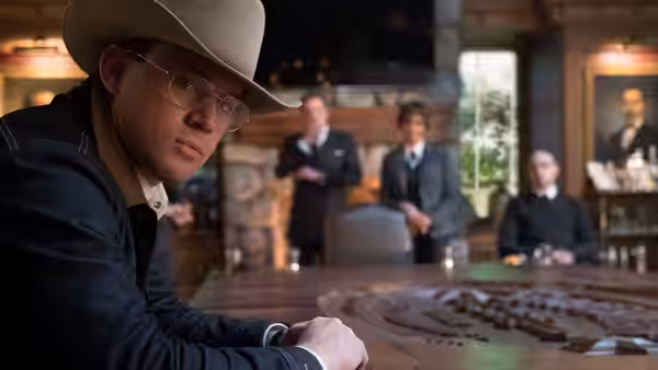 Tequila (Channing Tatum) sits at a table in a Western saloon as suited men watch