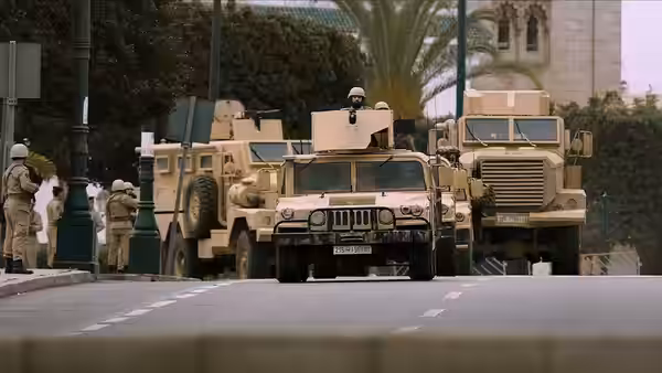 Armoured military vehicles lead a convoy down a city street