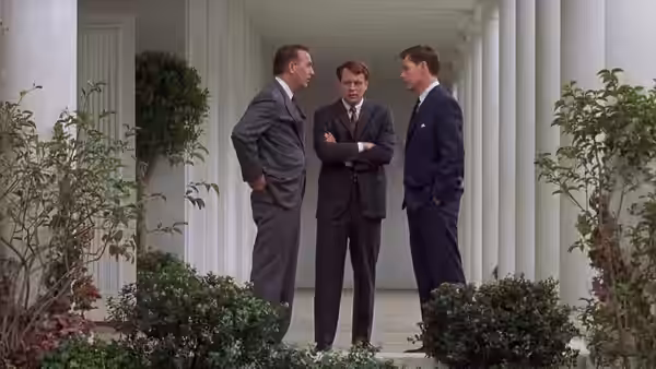 Kenneth O'Donnell (Kevin Costner) talks with two men beneath the White House colonnade