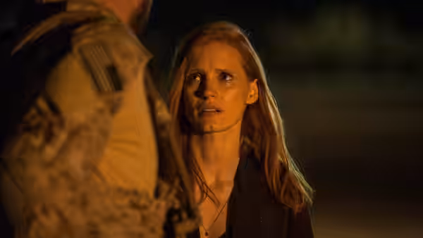 Maya (Jessica Chastain) speaking with a soldier outdoors at night