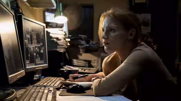 Maya (Jessica Chastain) monitoring screens at a cluttered office desk