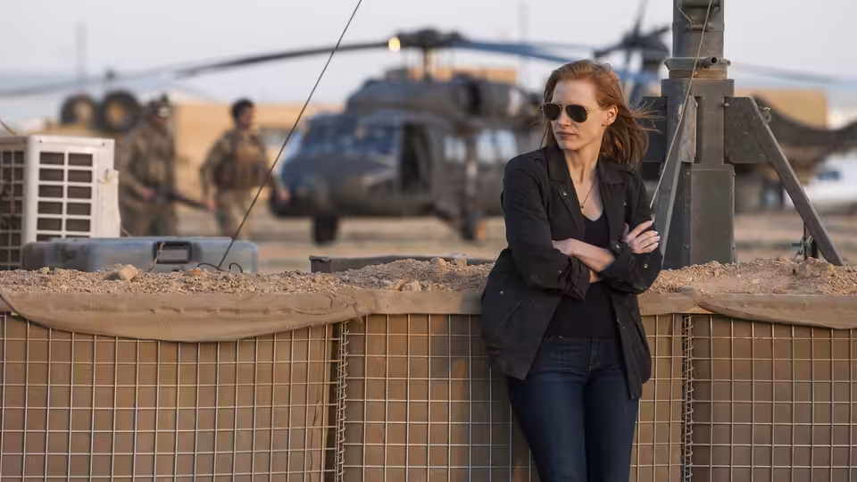 Maya (Jessica Chastain) leaning against sandbags at a military base