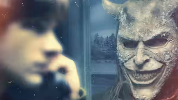 Finn (Mason Thames) holds a phone while facing a horned masked figure at the window