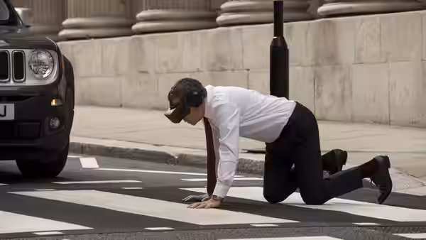 Johnny English (Rowan Atkinson) crawls across a pedestrian crossing in a virtual reality headset
