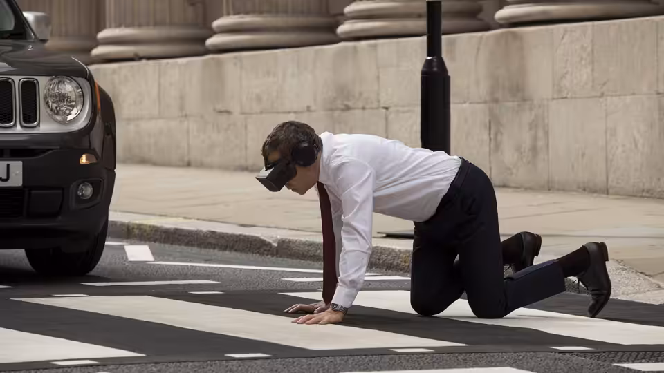 Johnny English (Rowan Atkinson) crawls across a pedestrian crossing in a virtual reality headset