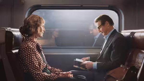 Michael MacCauley (Liam Neeson) reads a note opposite an older woman on the train